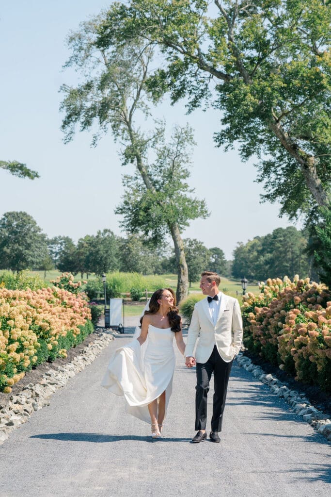 Bride and groom walking through gardens at Renault Winery during summer vineyard wedding in New Jersey